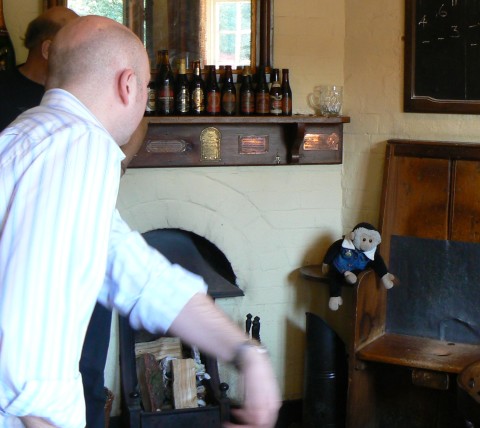The barman shows how to throw a penny into the hole