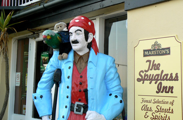 Mooch monkey sits with the parrot on the shoulder of the pirate outside the Spyglass Inn, Ventnor, Isle of Wight.