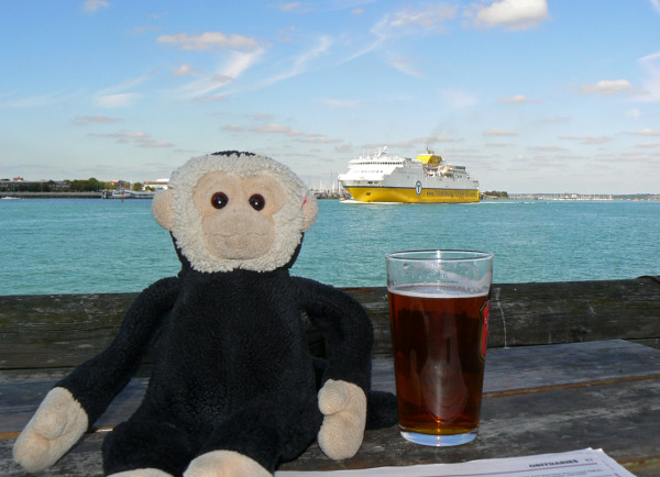 Mooch monkey with a beer at the Still & West Country House, Portsmouth with a large ferry passing.