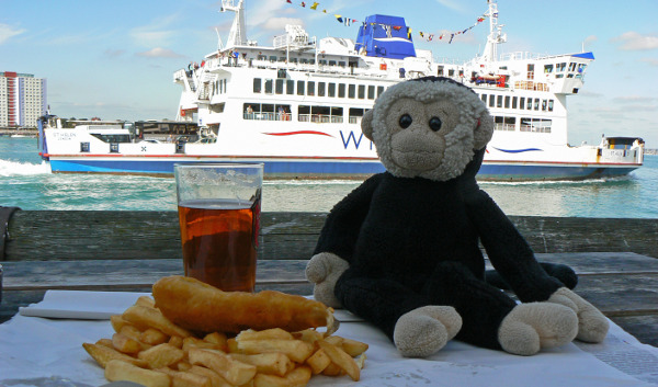 Mooch monkey with fish and chips at the Still & West Country House, Portsmouth, with an Isle of Wight ferry passing.