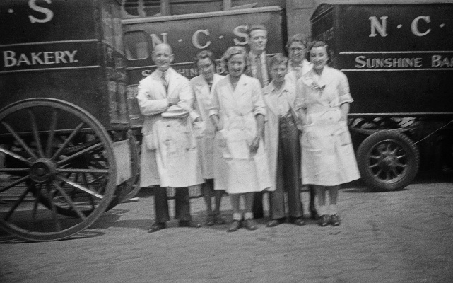 Una Brigg's (Jones) office worker colleagues on the NCS Bakery forecourt with horse drawn vans. 1941.