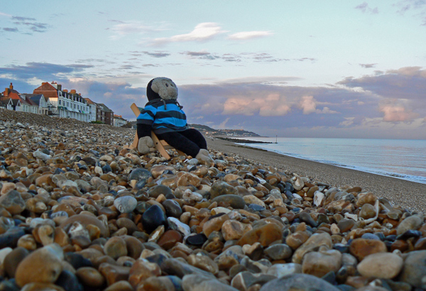 Mooch monkey sits in his deckchair on the beach at Hythe in Kent.