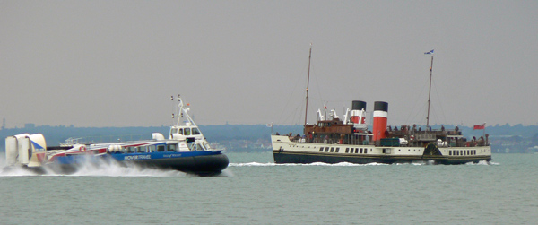 A hovercraft passing a paddle steamer.