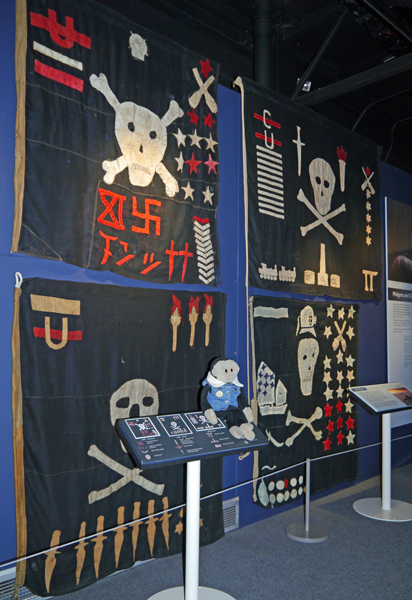 Mooch monkey at the Submarine Museum with Jolly Roger flags.